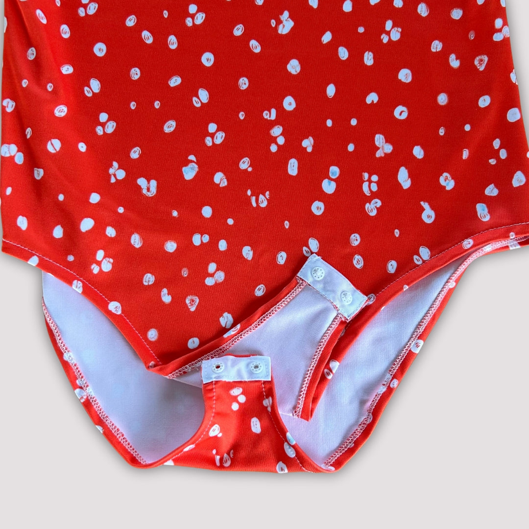 Body de mujer de hombros descubiertos con mangas abullonadas color rojo anaranjado con motas blancas y de tela de lycra elástica